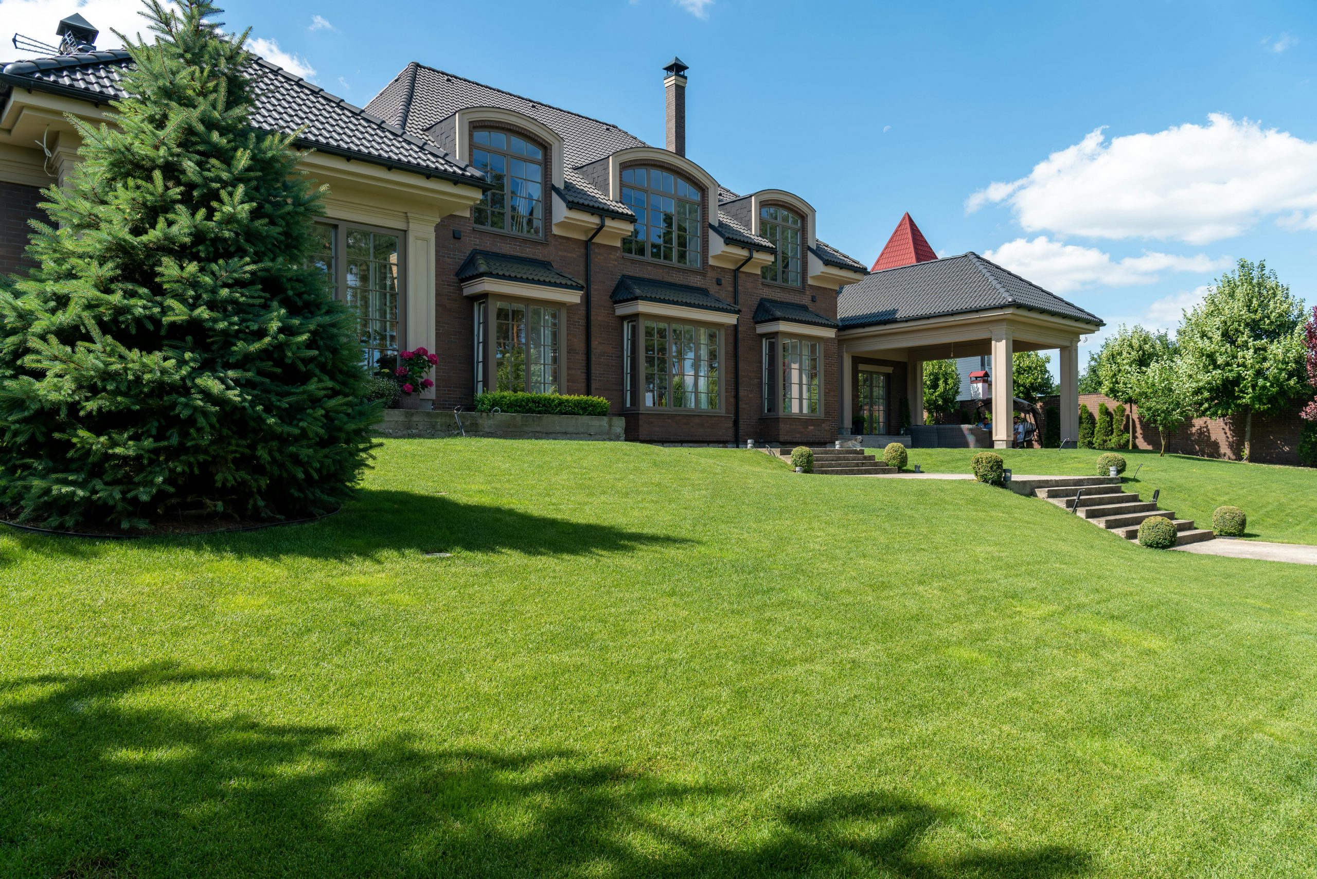 Luxury estate with manicured lawn and modern architectural design on a sunny day.